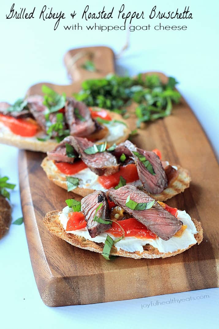 Grilled Ribeye & Roasted Pepper Bruschetta with Whipped Goat Cheese on crostini on a wooden board