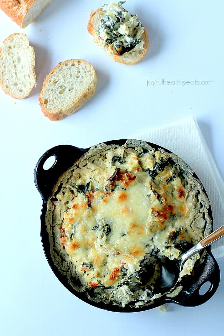 A Crock of Creamy Kale Spinach Artichoke Dip with Slices of Italian Bread