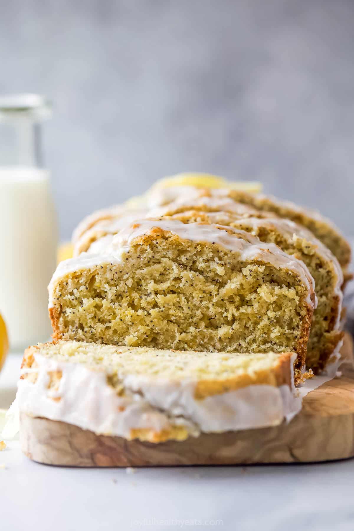 This lemon poppy seed bread is a zesty dessert-turned-breakfast packed with healthy ingredients like Greek yogurt for a guilt-free treat. Sliced loaf with a glass of milk in the background.