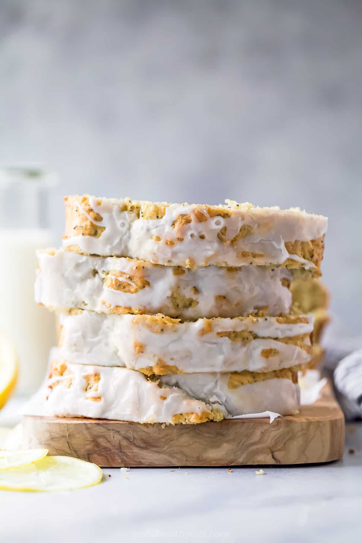 This lemon poppy seed bread is a zesty dessert-turned-breakfast packed with healthy ingredients like Greek yogurt for a guilt-free treat. Stack of glazed slices.