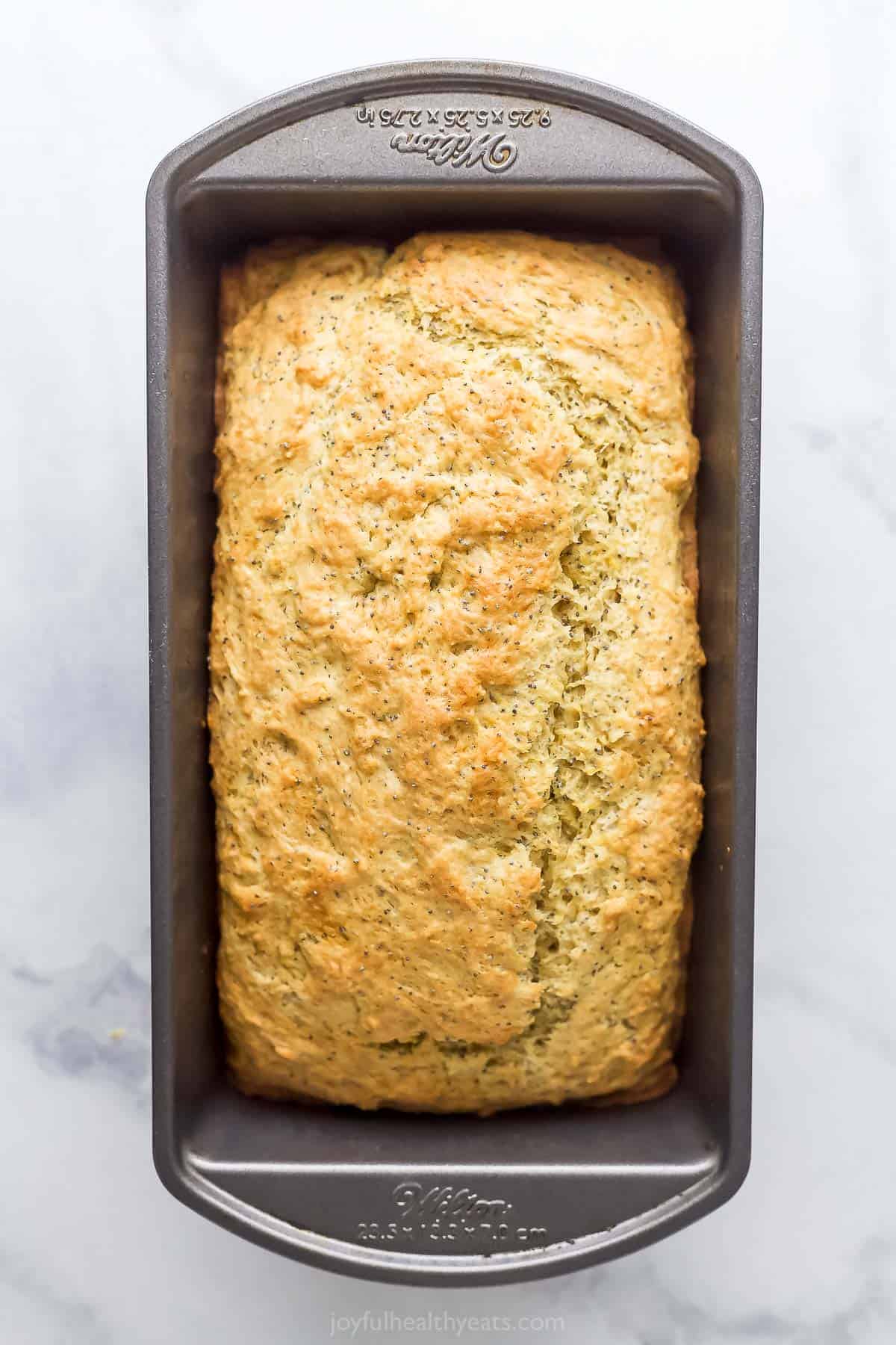 This lemon poppy seed bread is a zesty dessert-turned-breakfast packed with healthy ingredients like Greek yogurt for a guilt-free treat. Baked loaf in the baking pan.
