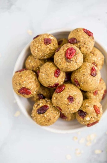 a bowl filled with pumpkin energy balls with cranberries