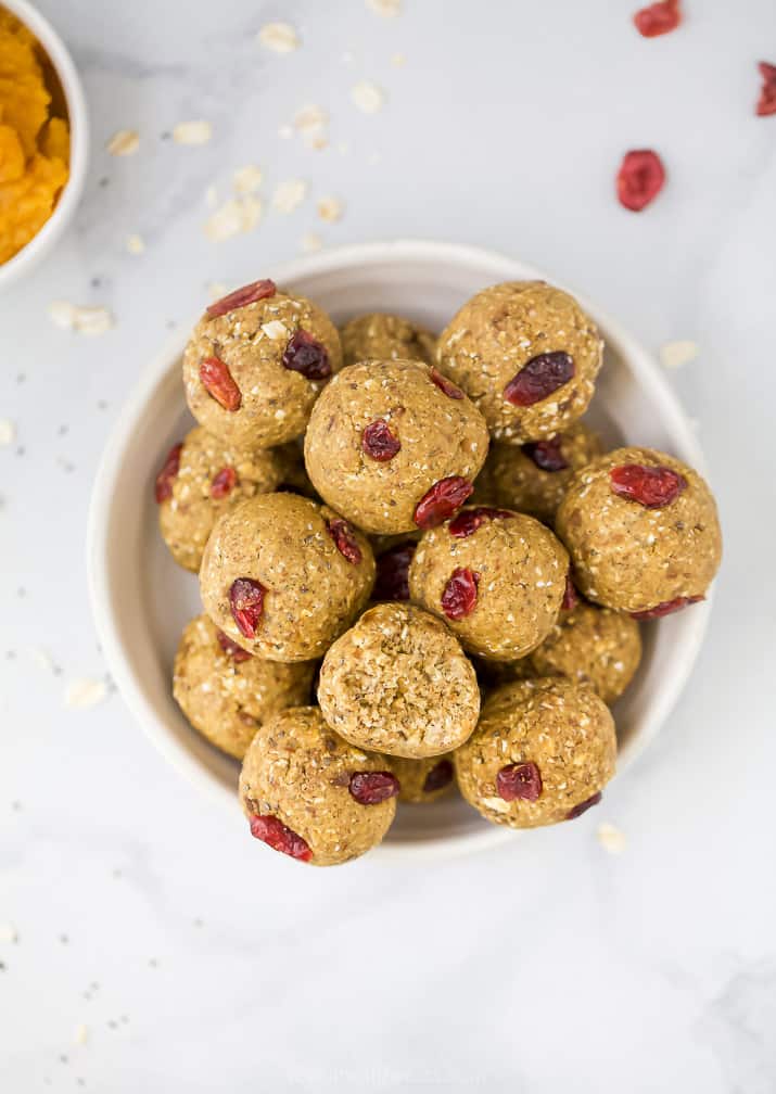 a bowl filled with pumpkin energy balls with cranberries in them