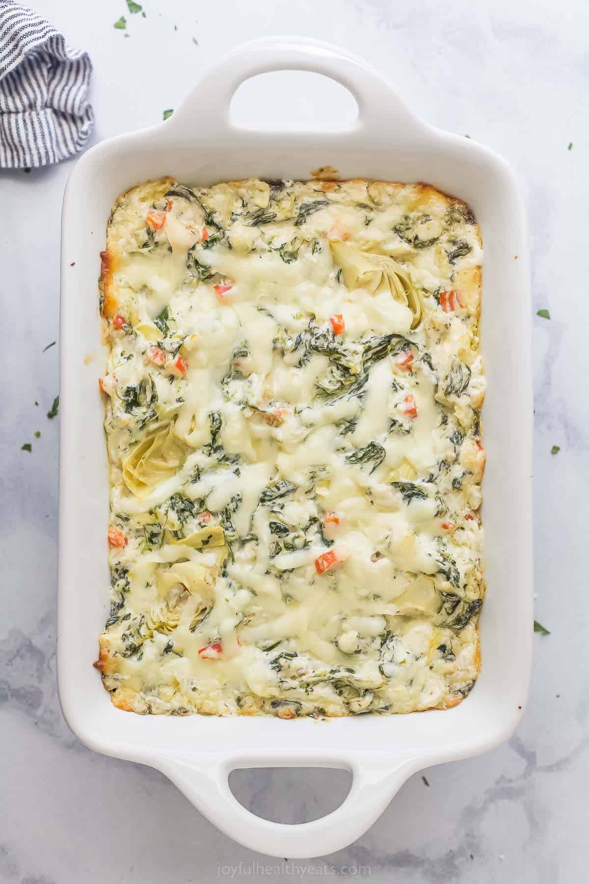 a casserole dish with hot spinach artichoke dip