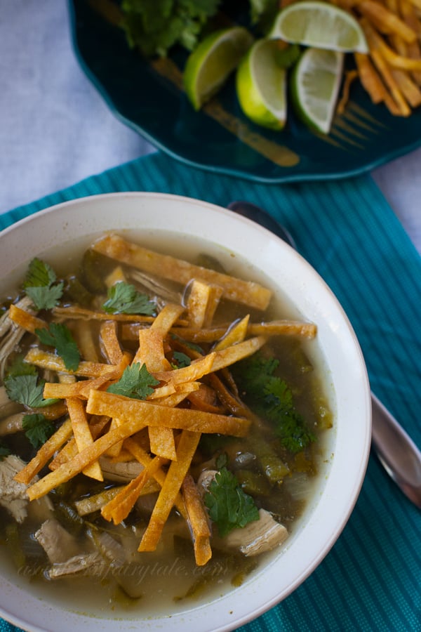 A Bowl of Chicken Poblano Soup Beside Four Lime Wedges