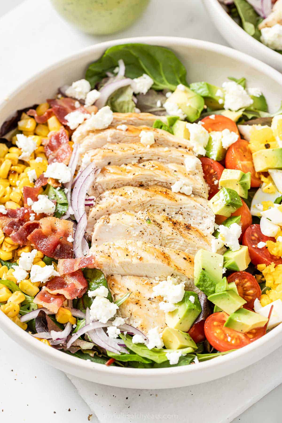 This hearty chicken Cobb salad is jazzed up with Tex-Mex flavors, from avocado and queso fresco to a creamy and tangy poblano dressing! Chicken Cobb salad in bowl before adding dressing