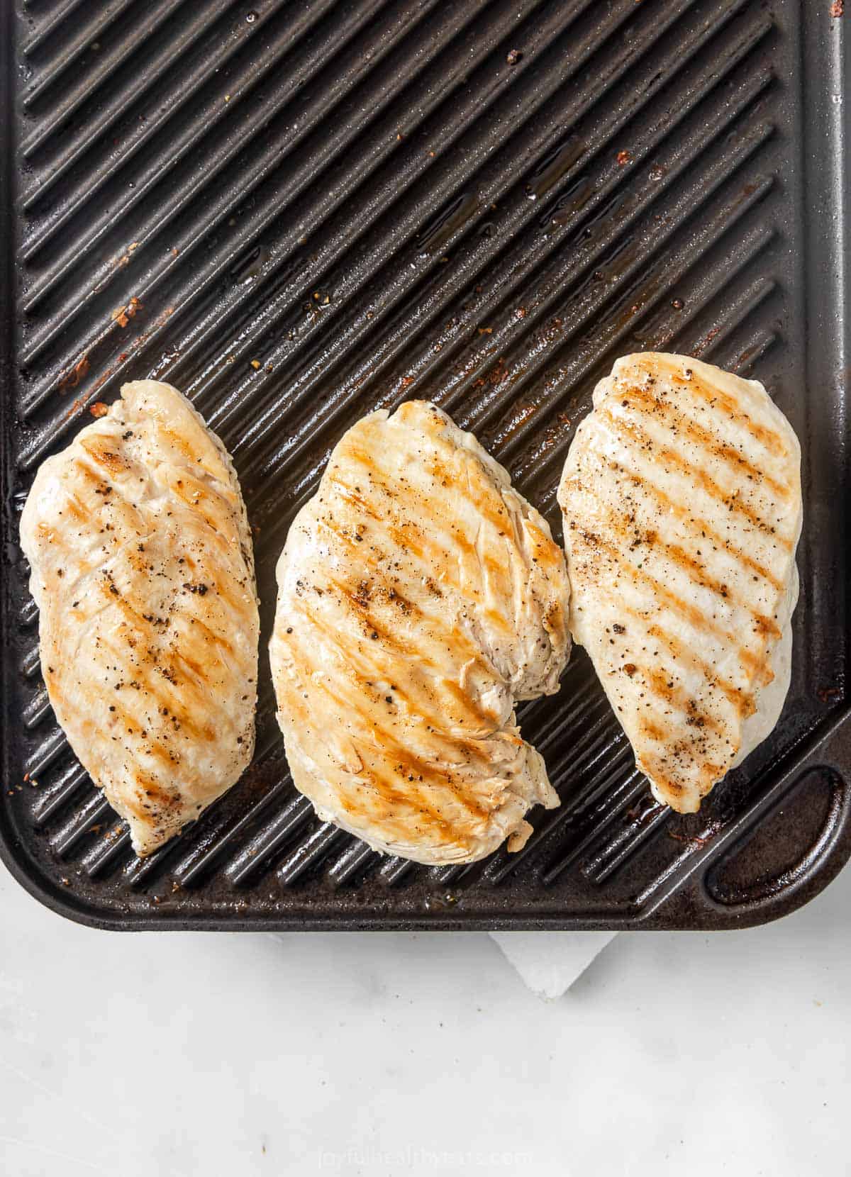This hearty chicken Cobb salad is jazzed up with Tex-Mex flavors, from avocado and queso fresco to a creamy and tangy poblano dressing! Overhead view of chicken cooking on indoor grill