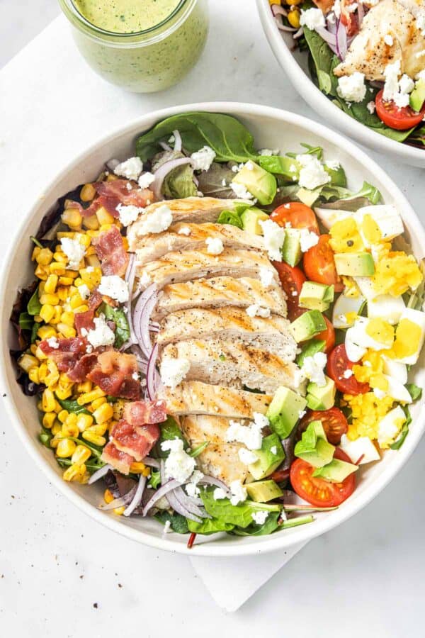 This hearty chicken Cobb salad is jazzed up with Tex-Mex flavors, from avocado and queso fresco to a creamy and tangy poblano dressing! Chicken Cobb salad in bowl