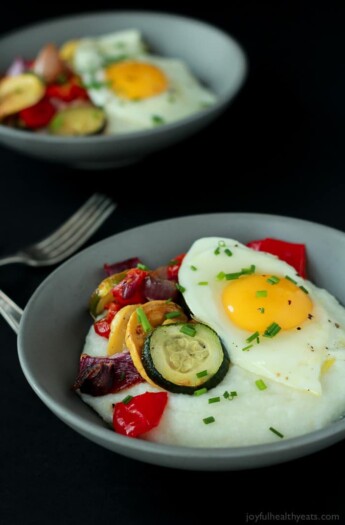 Two Bowls of Grits with Eggs & Veggies Beside Two Forks