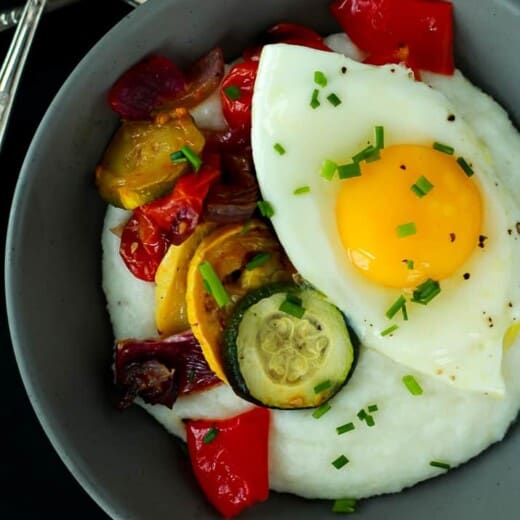 A Close-up View of a Bowl of Grits with a Fork in the Background