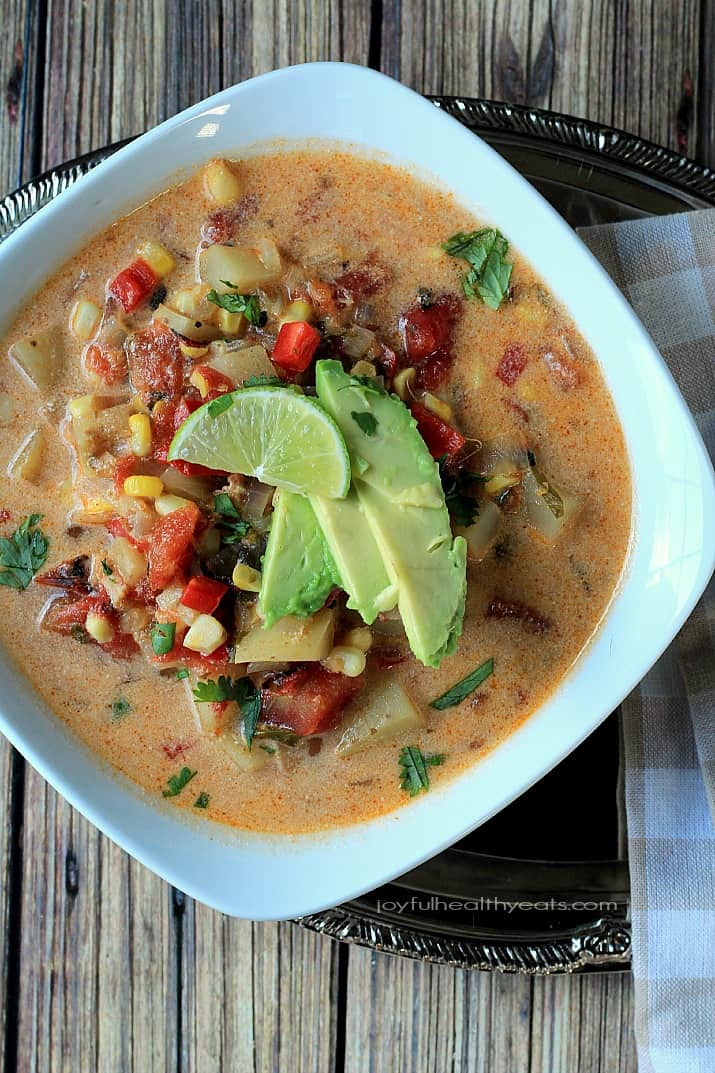 Top view of a bowl of Southwestern Corn & Potato Chowder topped with sliced avocado and lime