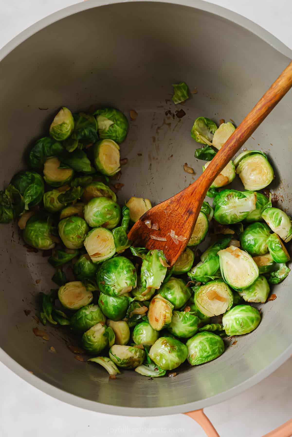 Cooking the brussels sprouts with the onions in the pan. 
