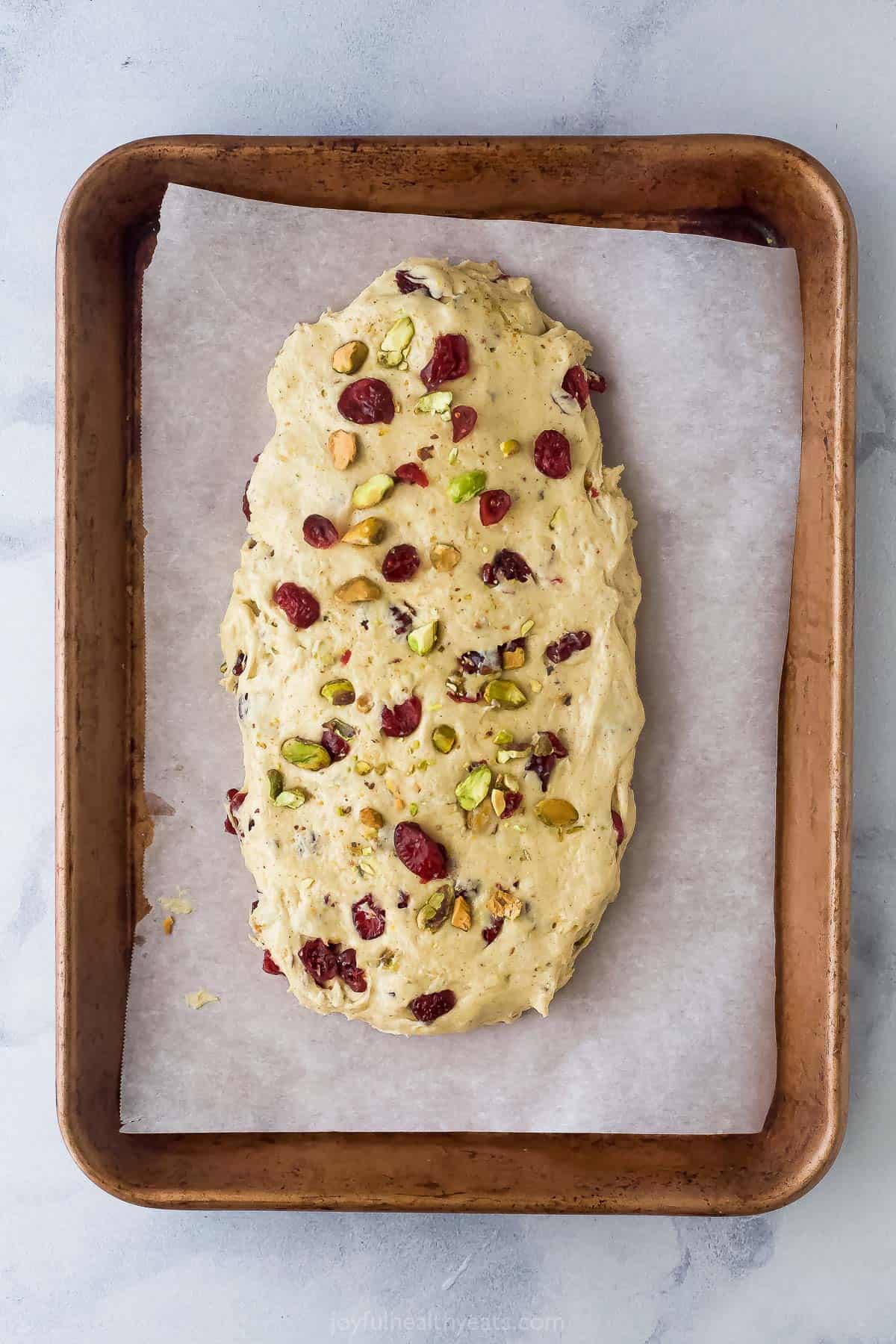 A log of biscotti dough on a metal baking sheet lined with parchment paper