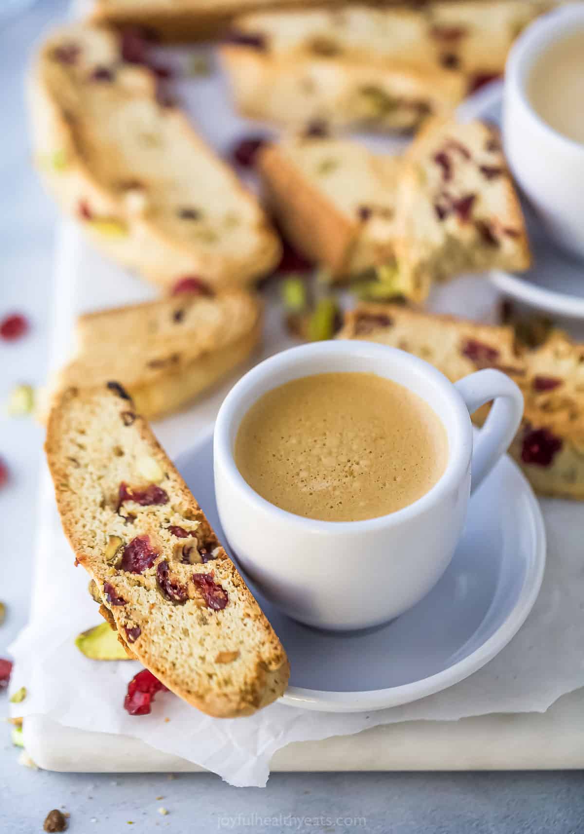 A cup of coffee on top of a saucer with a homemade biscotti cookie