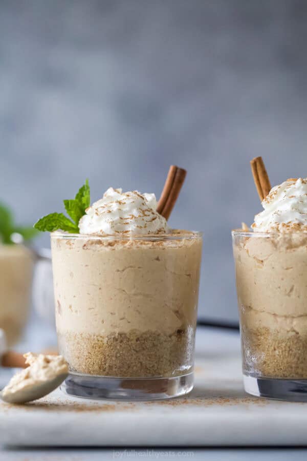 A glass of no bake pumpkin cheesecake with Cool Whip and cinnamon on top.