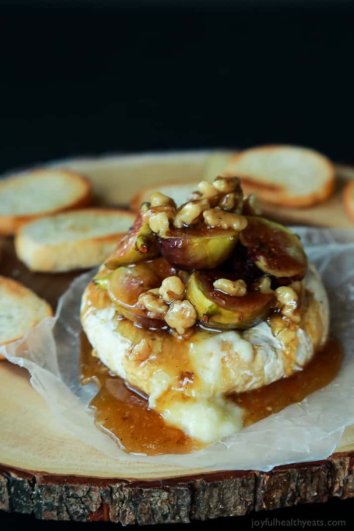 Baked Brie with Roasted Fig Honey Walnut Topping on a Wooden Surface