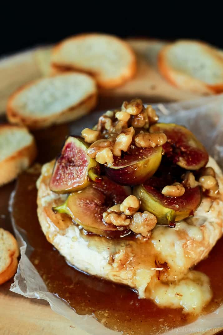 Baked Brie with Roasted Fig Honey Walnut Topping on a serving board with crostini