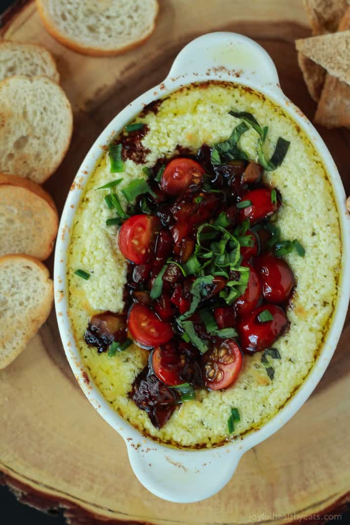 Top view of Baked Goat Cheese Dip topped with balsamic bruschetta and surrounded by crostini