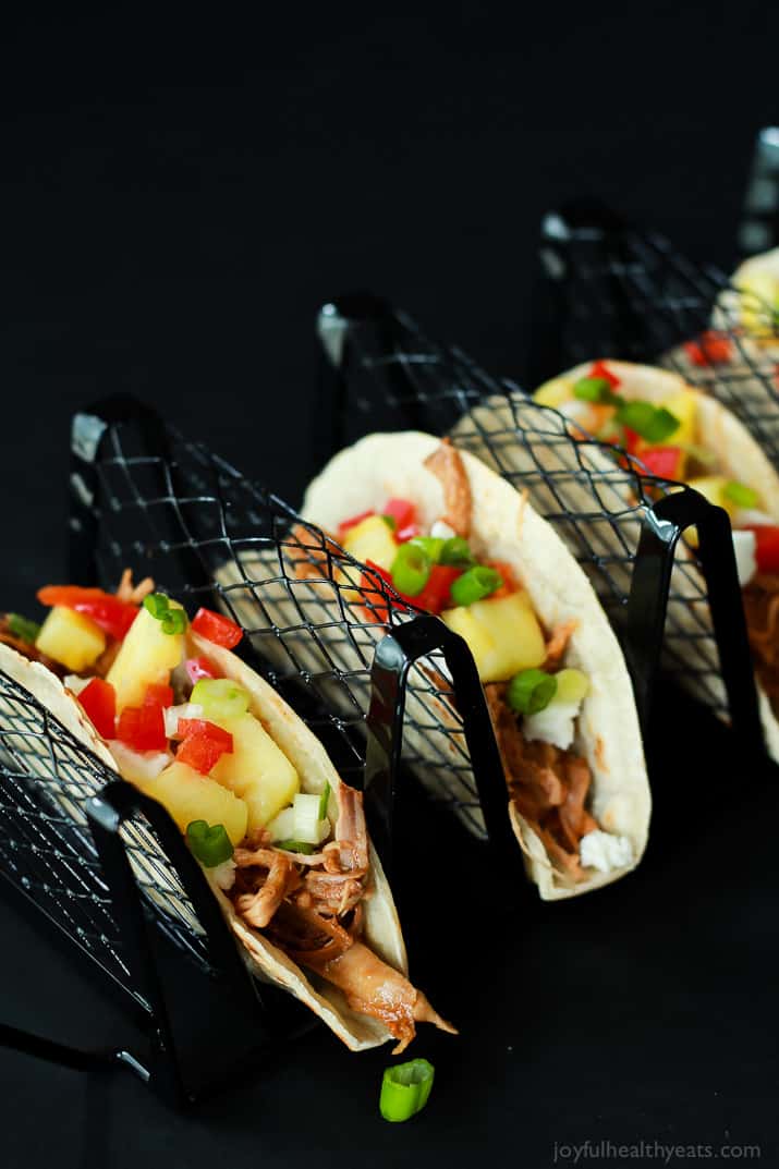 Hawaiian Pork Tacos filled with sweet pulled pork, fresh pineapple, red peppers, and goat cheese in a taco holder rack