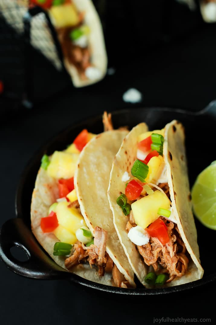 Two Hawaiian Pork Tacos filled with sweet pulled pork, fresh pineapple, red peppers, and goat cheese