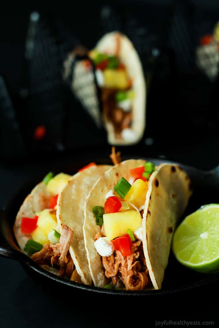 Two Hawaiian Pork Tacos filled with sweet pulled pork, fresh pineapple, red peppers, and goat cheese