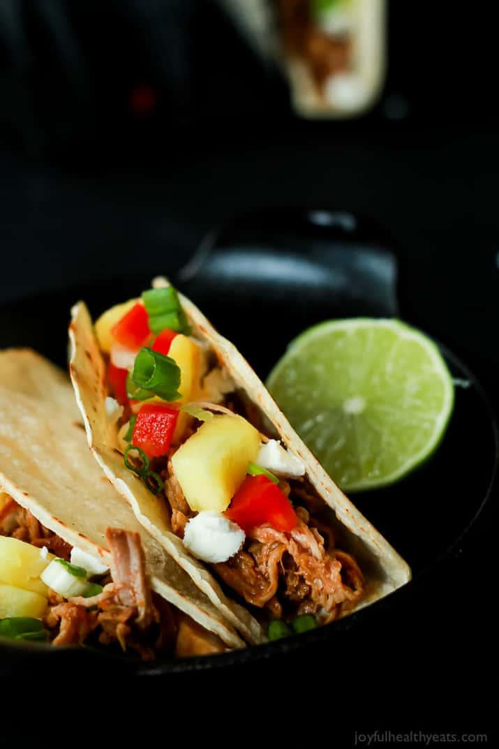 Two Hawaiian Pork Tacos filled with sweet pulled pork, fresh pineapple, red peppers, and goat cheese