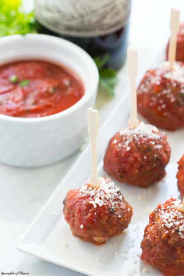 Mozzarella Stuffed Italian Meatballs Next to a Container of Tomato Sauce