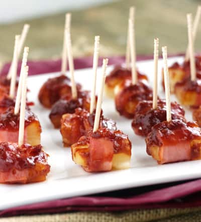 Sweet and Sower Bacon Wrapped Pineapple Pops on a Piece of Parchment Paper