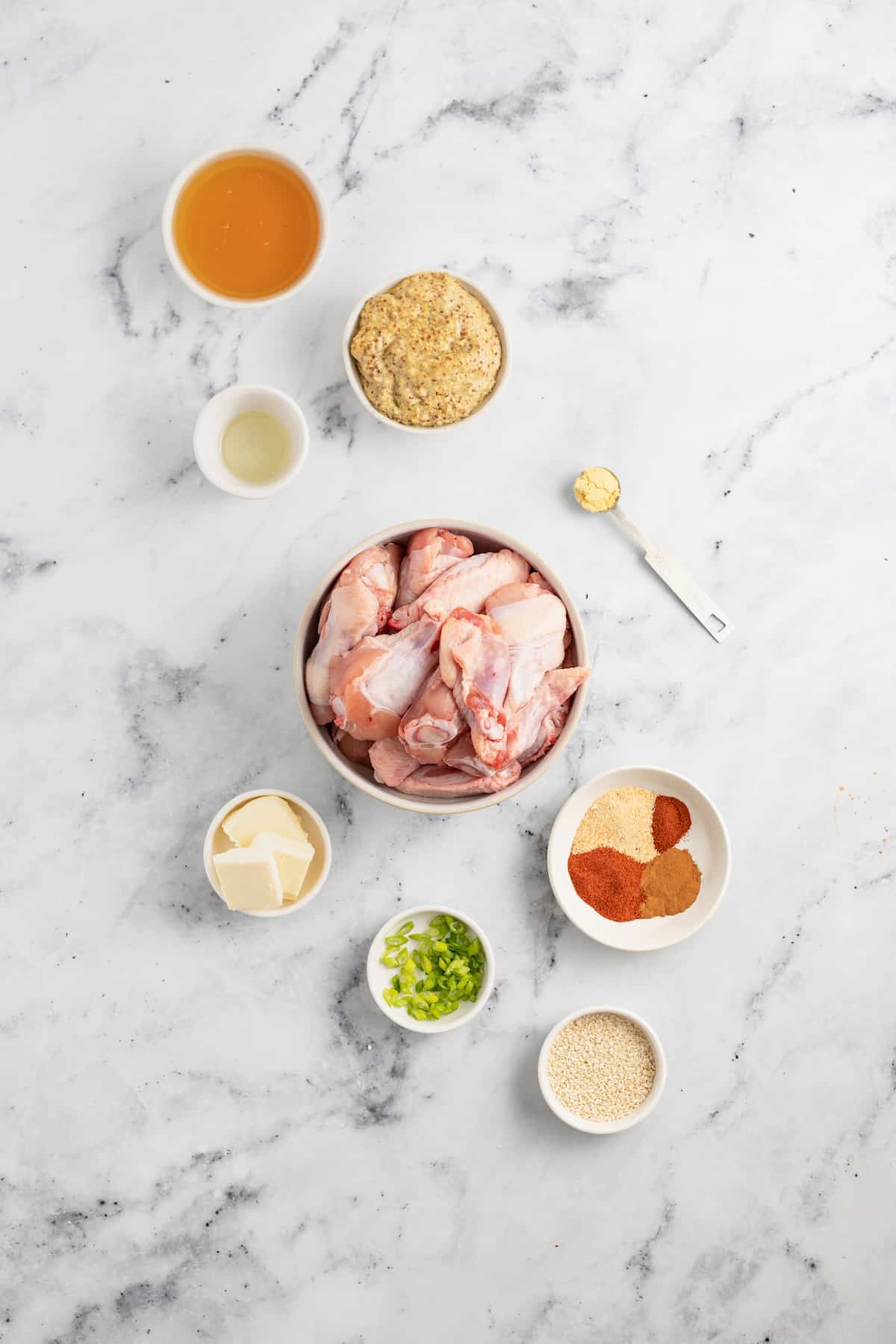 ingredients to make baked chicken wings like chicken, seasonings, butter, and mustard