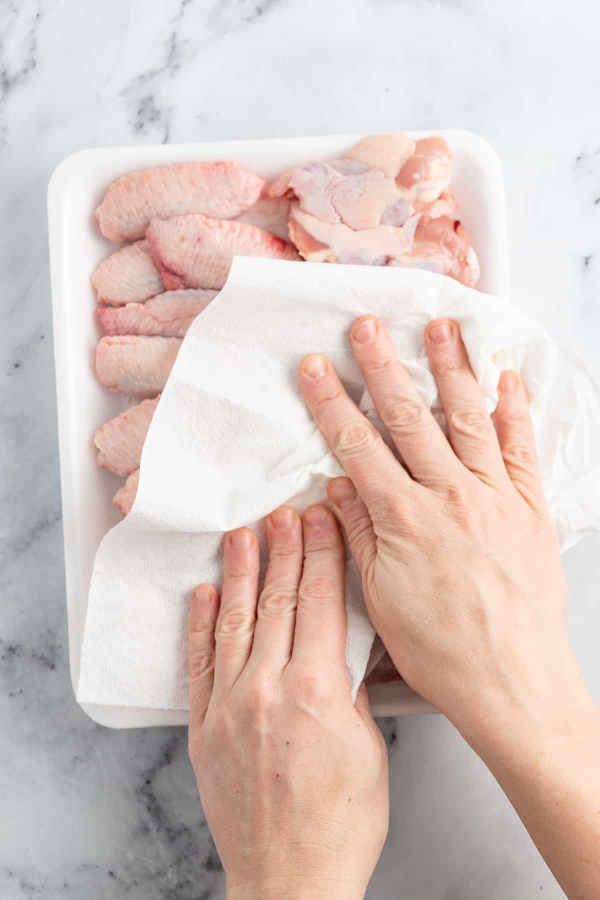 patting chicken wings dry with a paper towel