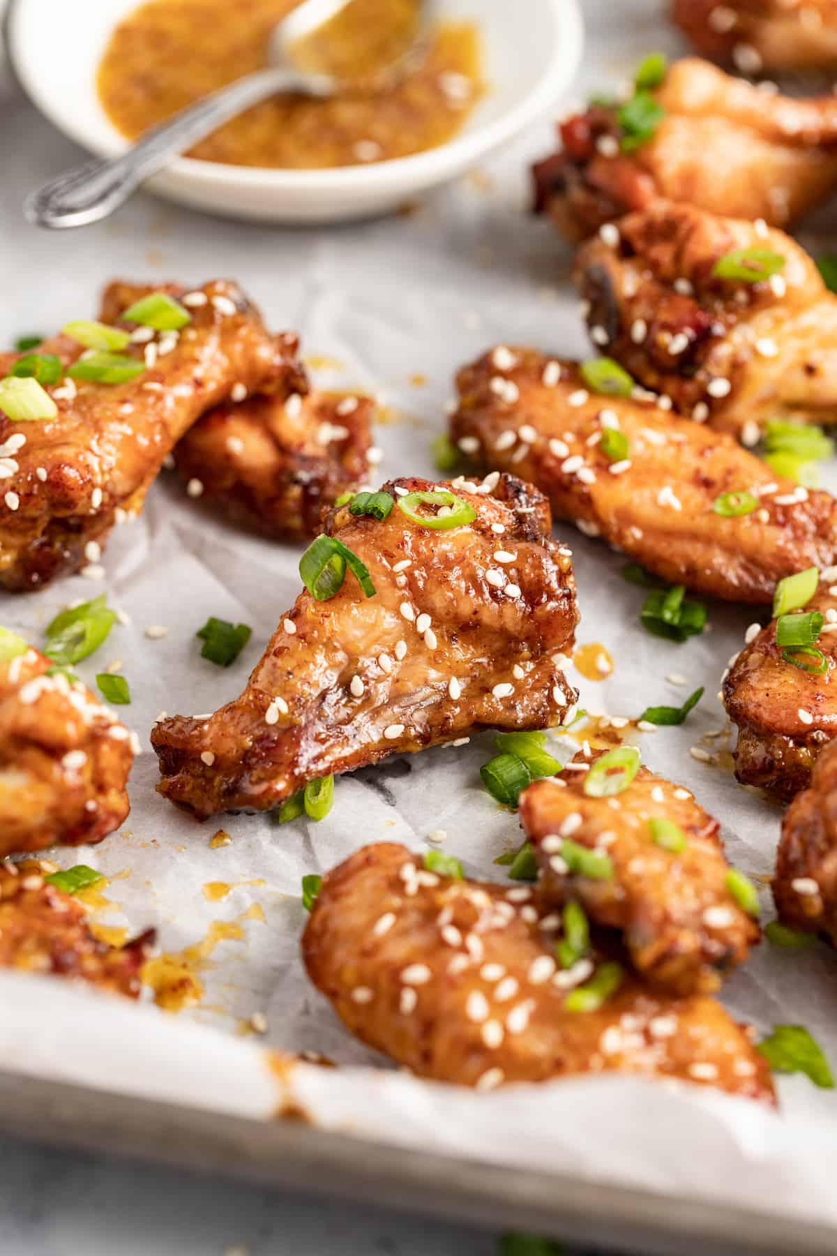 baked chicken wings on a lined sheet tray with sesame seed and herb garnish