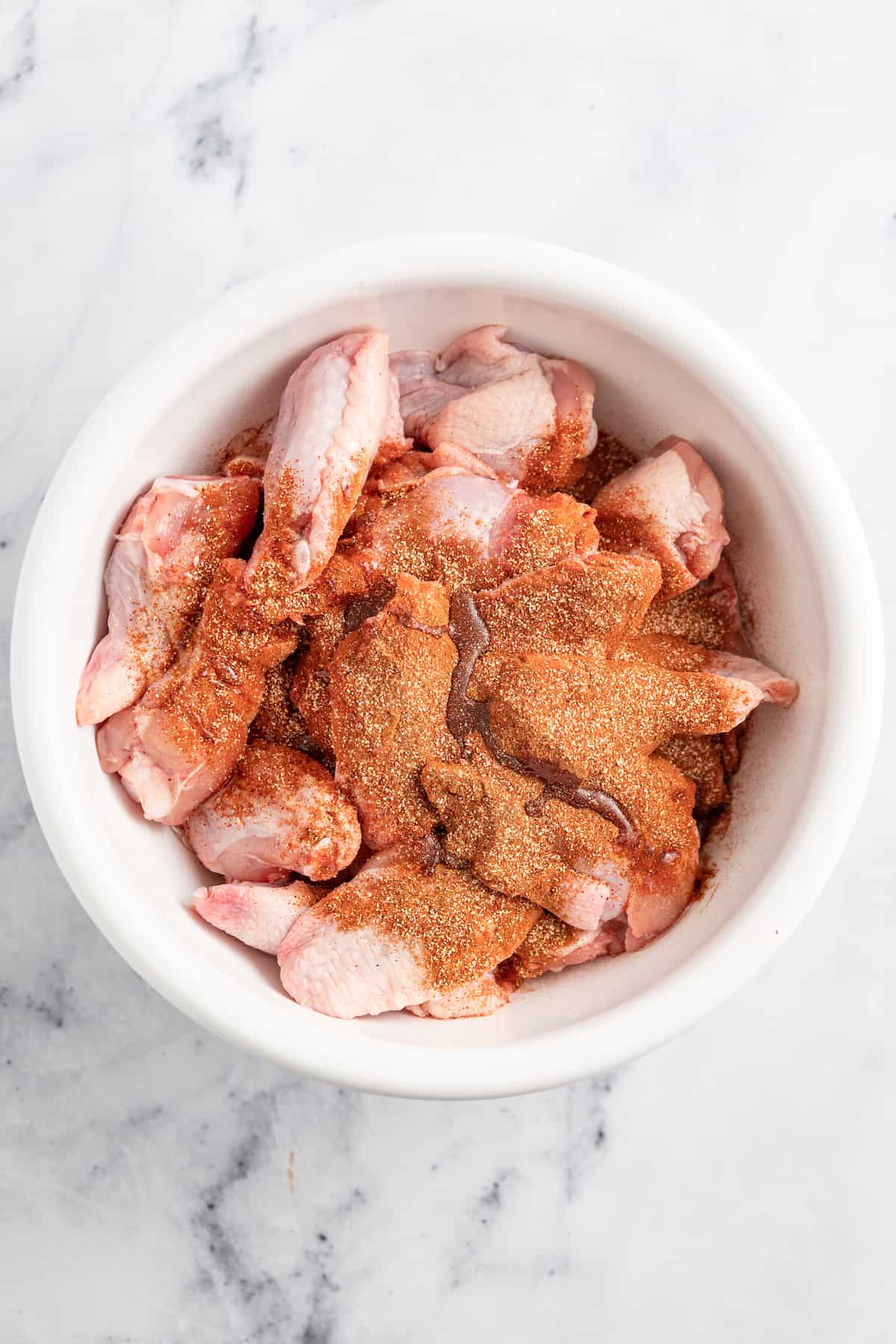 seasoning blend on top of chicken wings in a bowl