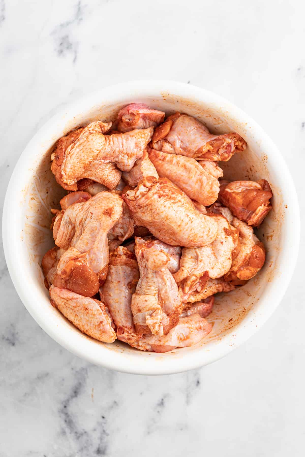 Honey Mustard Baked Chicken Wings are a fun appetizer to make for your next party. It has an easy honey mustard saucethat everyone will love. raw chicken wings in a bowl