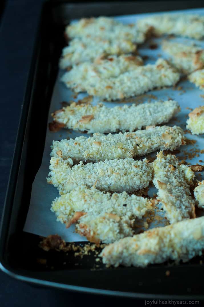 Coconut Crusted Chicken Tenders on a parchment-lined baking sheet