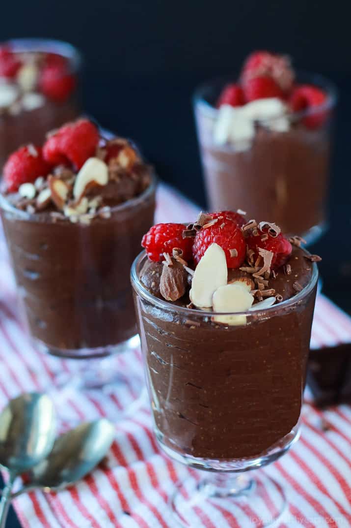 Dessert glasses of Chocolate Chia Pudding, topped with sliced almonds, shaved chocolate and fresh raspberries