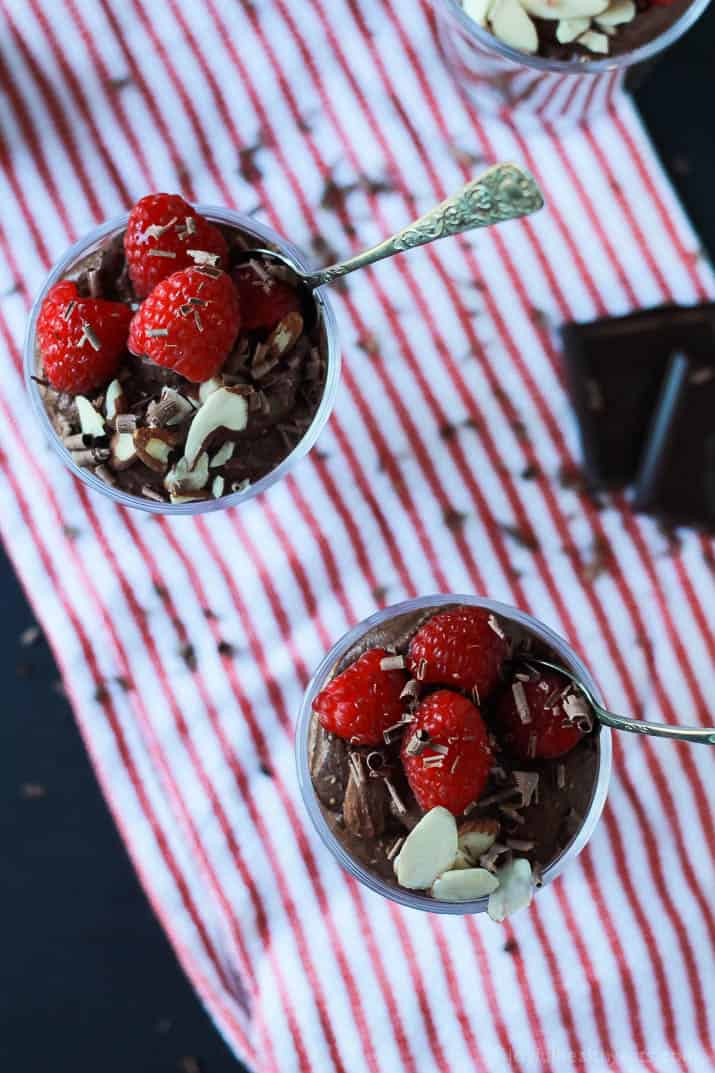 Top view of dessert glasses of Chocolate Chia Pudding, topped with sliced almonds, shaved chocolate and fresh raspberries