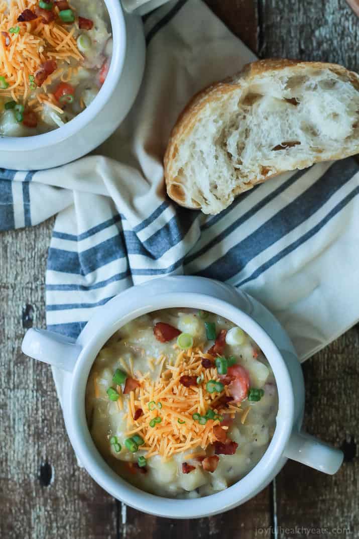 Top view of two crocks of Creamy Potato Leek Soup next to a piece of crusty bread