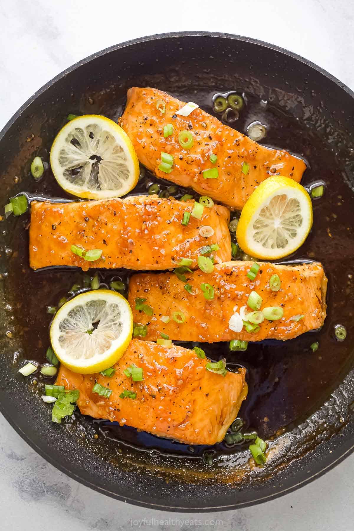 Four salmon fillets with glaze in the pan.