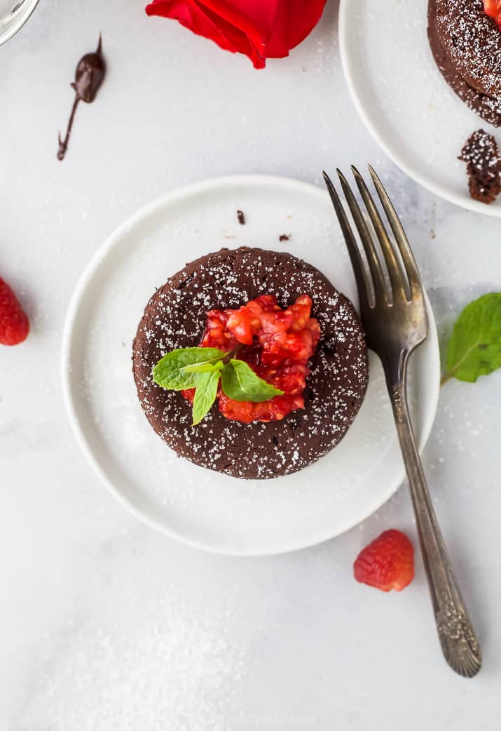 overhead photo of nutella chocolate lava cake topped with champagne muddled raspberries on a plate