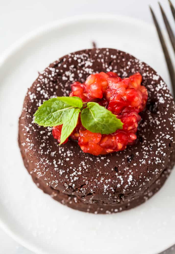 close up photo of photo of nutella chocolate lava cake topped with champagne muddled raspberries