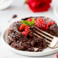 photo of half eaten nutella chocolate lava cake with chocolate oozing out topped with champagne muddled raspberries