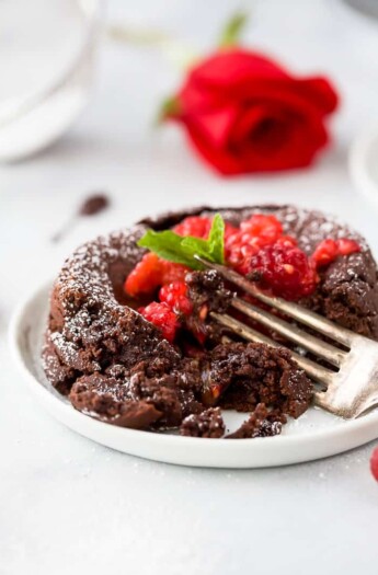 photo of half eaten nutella chocolate lava cake with chocolate oozing out topped with champagne muddled raspberries