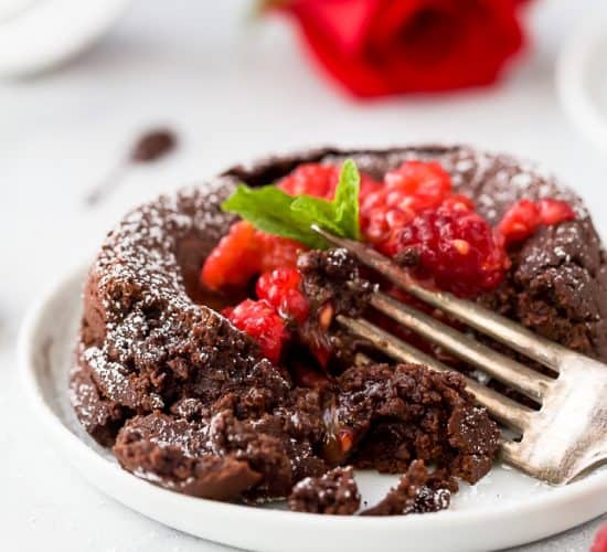 photo of half eaten nutella chocolate lava cake with chocolate oozing out topped with champagne muddled raspberries