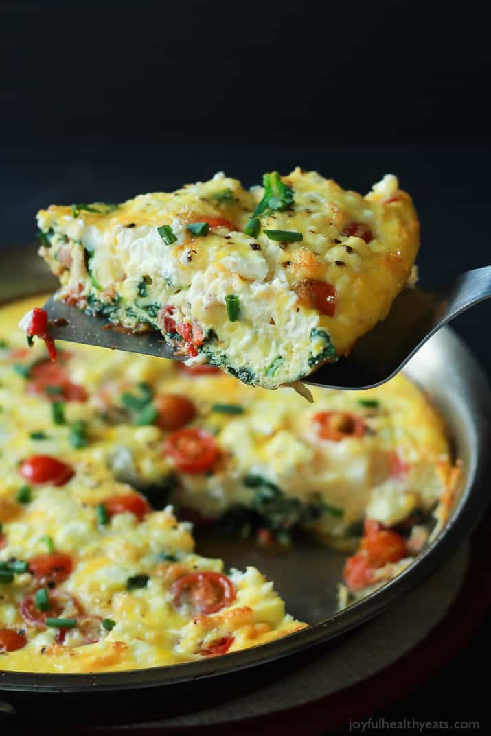 One Slice of Cheesy Bacon Spinach Frittata on a Spatula Over the Remaining Frittata