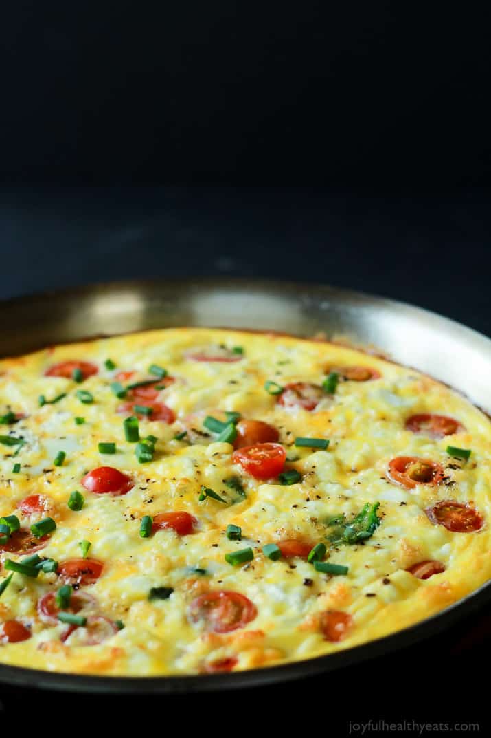 Cheesy Bacon Spinach Frittata with grape tomatoes in a skillet
