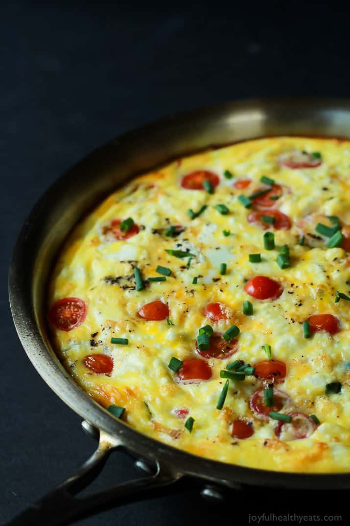 Cheesy Bacon Spinach Frittata with grape tomatoes in a skillet