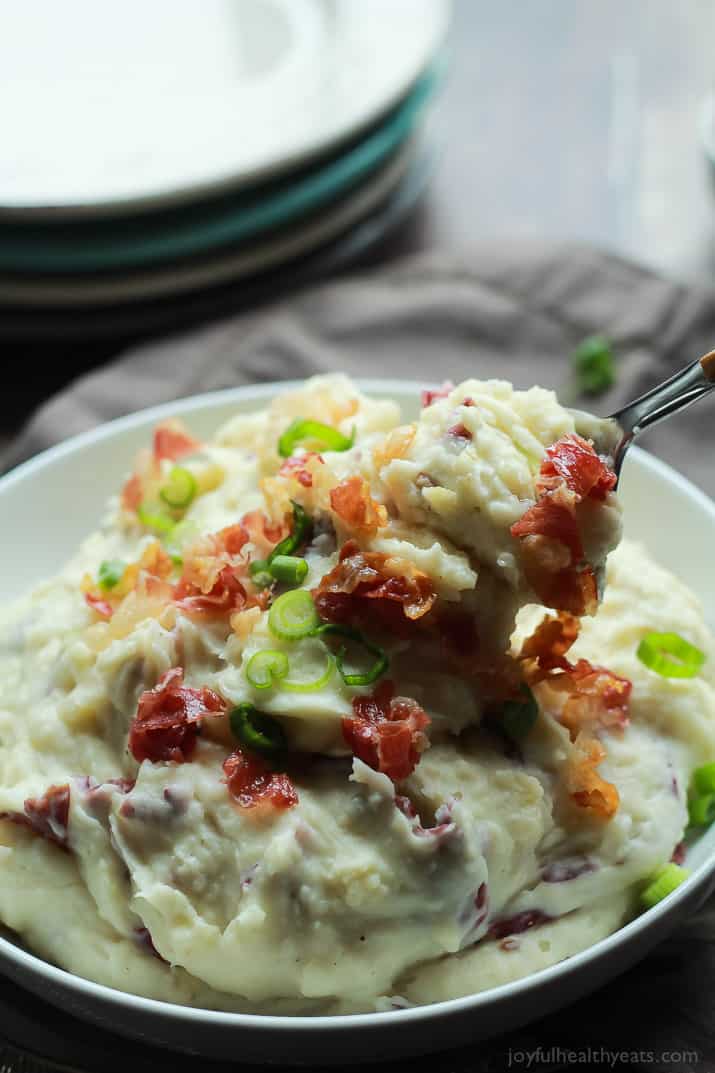 A Bowl of Creamy Goat Cheese Horseradish Mashed Potatoes with a Metal Spoon Scooping Up a Large Bite