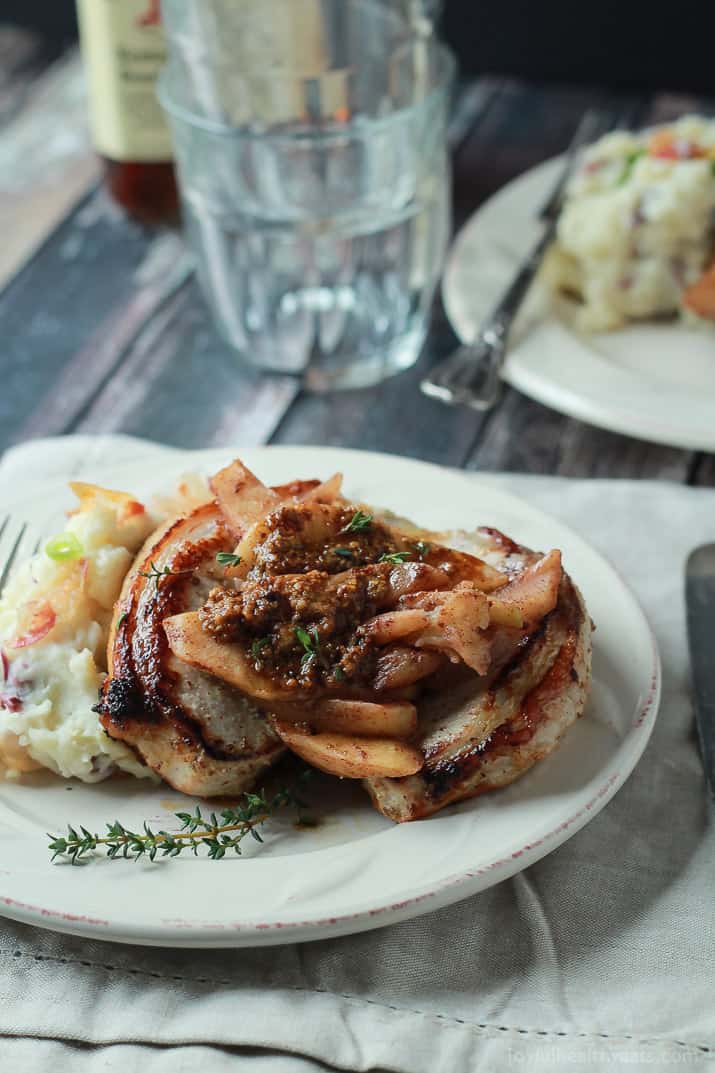 Mustard Crusted Pork Chops with Bourbon Glazed Apples on a Plate with Two Glasses in the Background