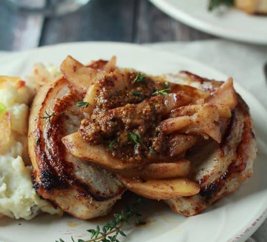 Mustard Crusted Pork Chops with Bourbon Glazed Apples on a White Plate