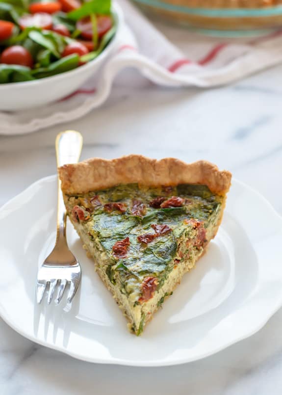 A Slice of Pesto Quiche with Sundried Tomatoes & Parmeson on a Plate with a Fork